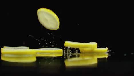 Juicy-fret-slices-fall-on-the-table-with-reflection-and-spray.-Slow-motion-of-a-ring-of-yellow-ripe-lemon.